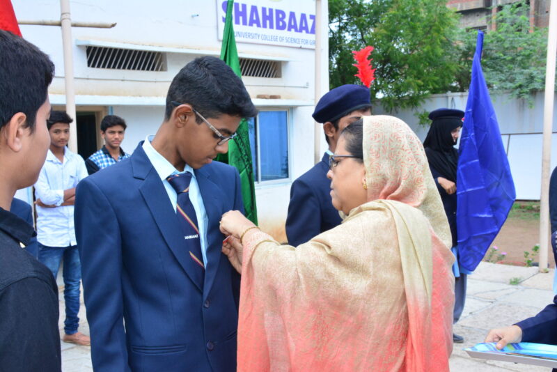 A students gets his badge from a teacher at Shahbaaz school and PU college