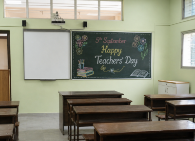 Teachers' Day Event Featured Image displaying a classroom with a blackboard decorated with colourful chalk art and Happy Teachers' Day